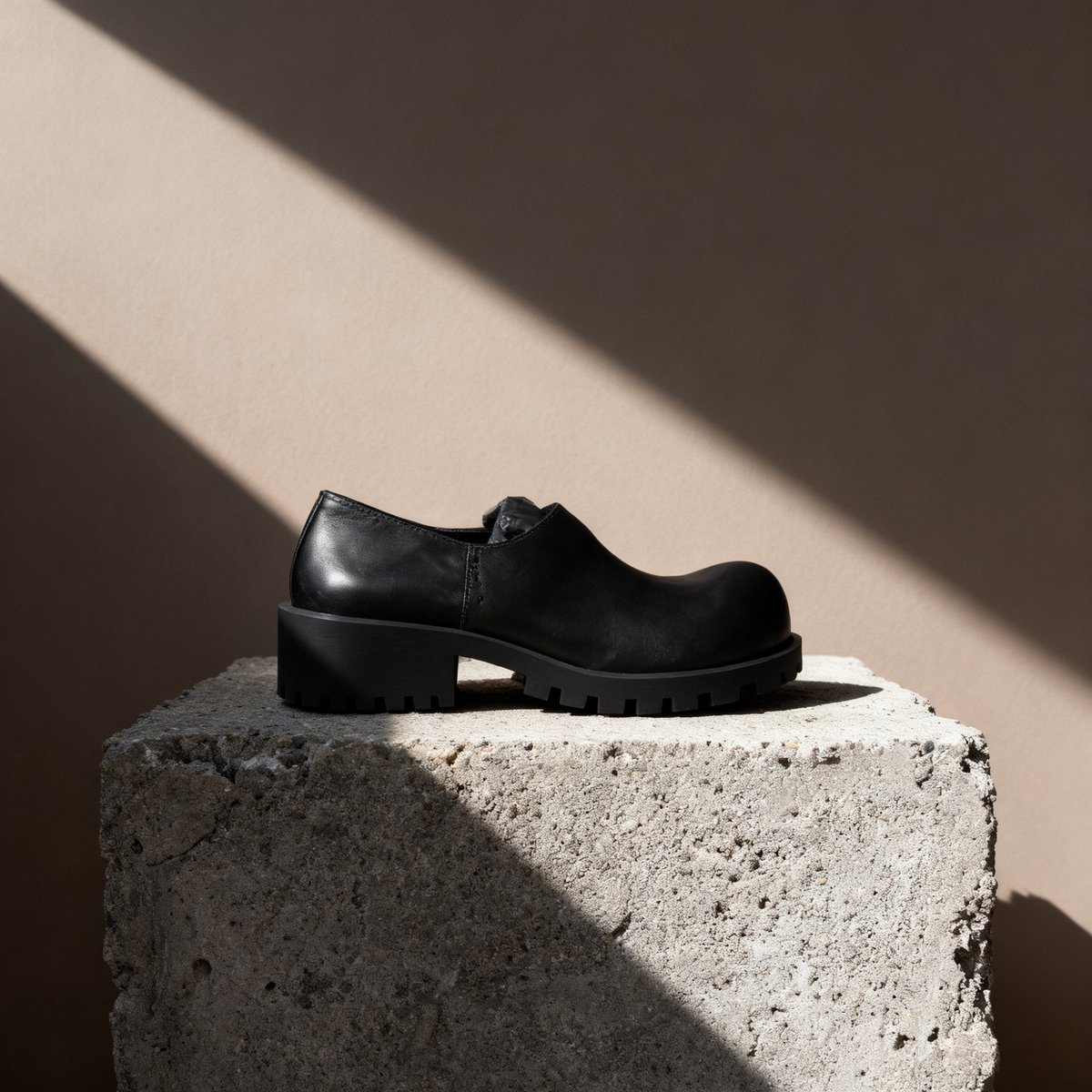 Black leather shoe on a concrete block in hard morning light, AI product shot